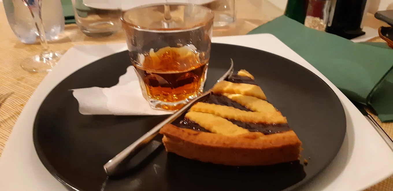 Crostata al cioccolato servita con un bicchiere di amaro