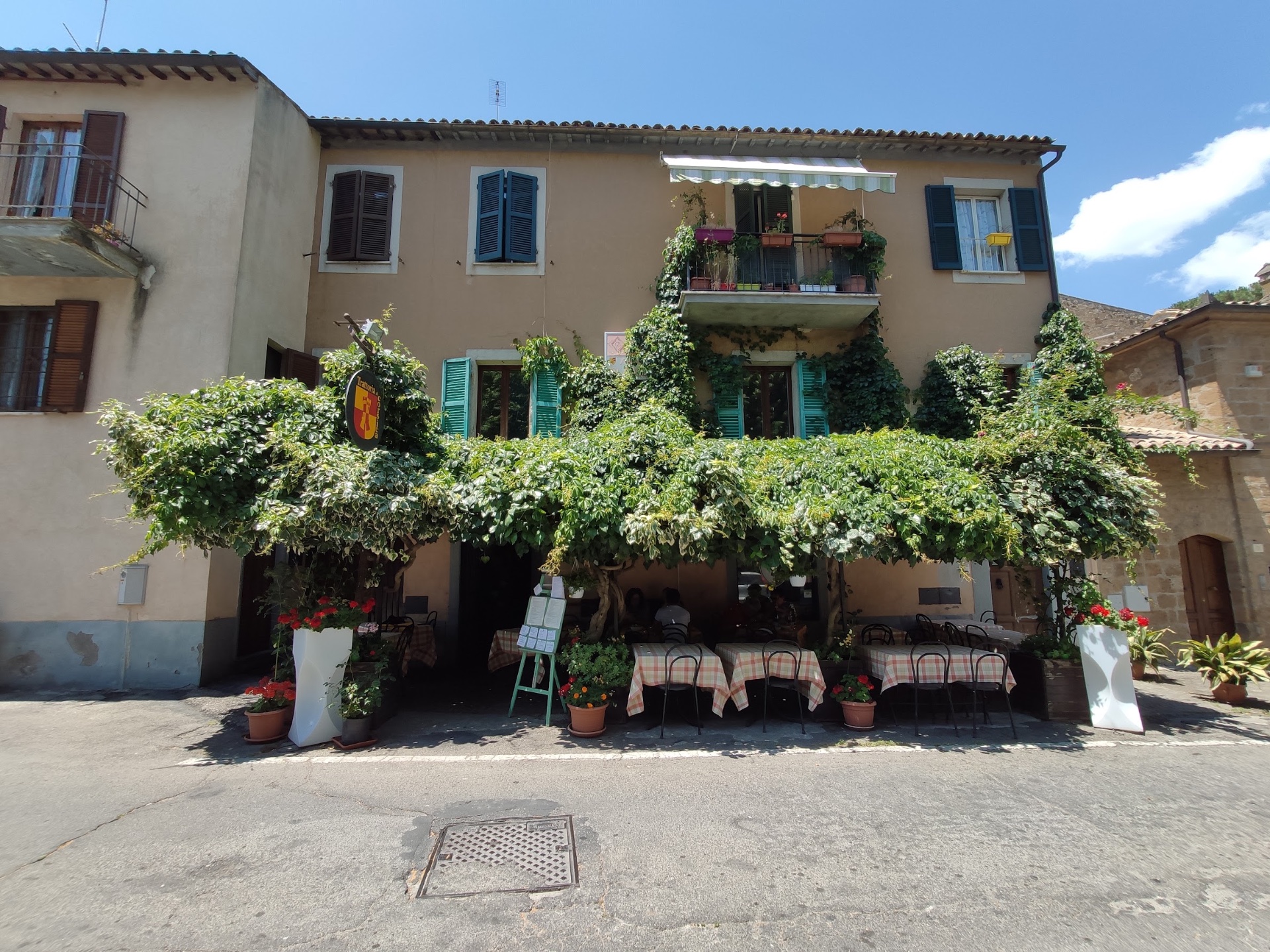 Facciata della trattoria di giorno con pergolato verde