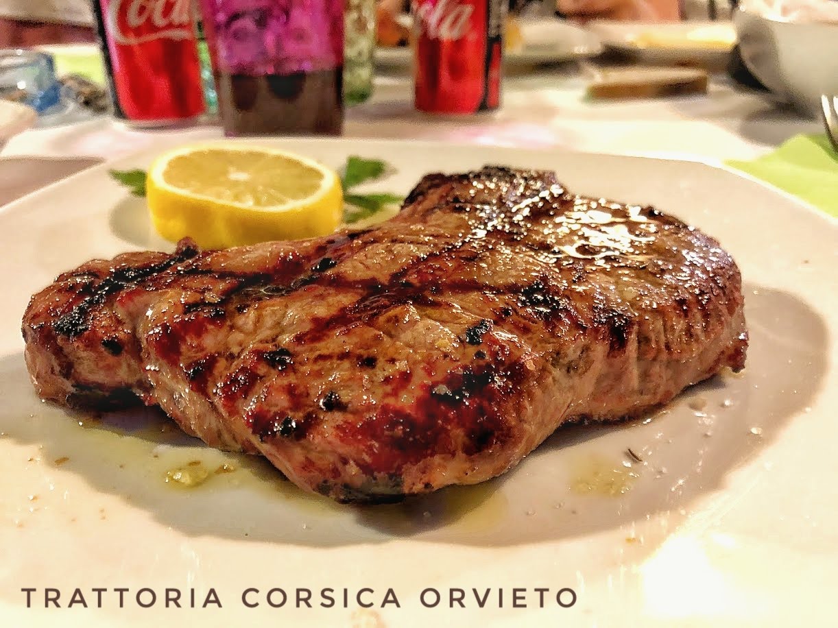 Bistecca alla griglia con segni di cottura, servita con mezzo limone e prezzemolo